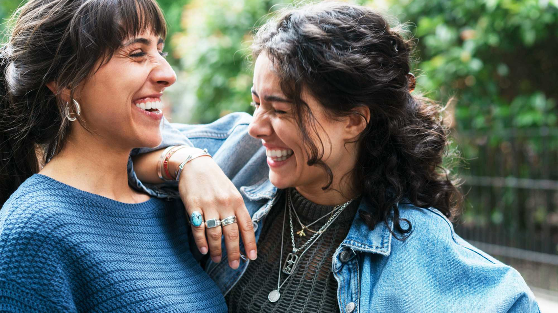 Frau lächelt und lehnt sich an die Schulter ihrer Freundin. | © Getty Images/Tim Robberts